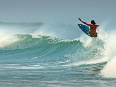 "Surfer riding the waves at Tamarindo Beach, Costa Rica, with clear blue skies and the vibrant ocean in the background." 🌊🏄‍♂️☀️