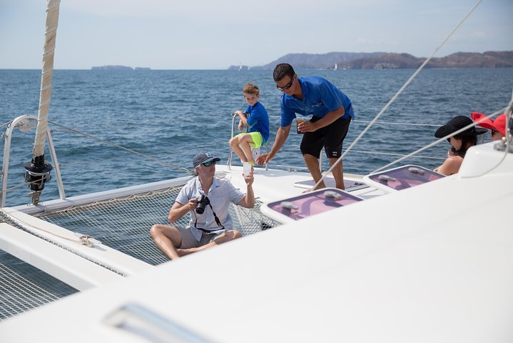 "Scenic sailing tour at Flamingo Beach, Costa Rica, with stunning ocean views, a sailboat gliding through calm waters, and a vibrant sunset in the background
