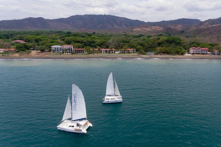 Scenic sailing tour at Flamingo Beach, Costa Rica, with stunning ocean views, a sailboat gliding through calm waters, and a vibrant sunset in the background."