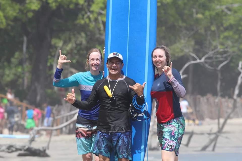 Surf lesson in Tamarindo, Costa Rica, with a professional instructor guiding students on the beach as they practice surfing techniques on the waves."