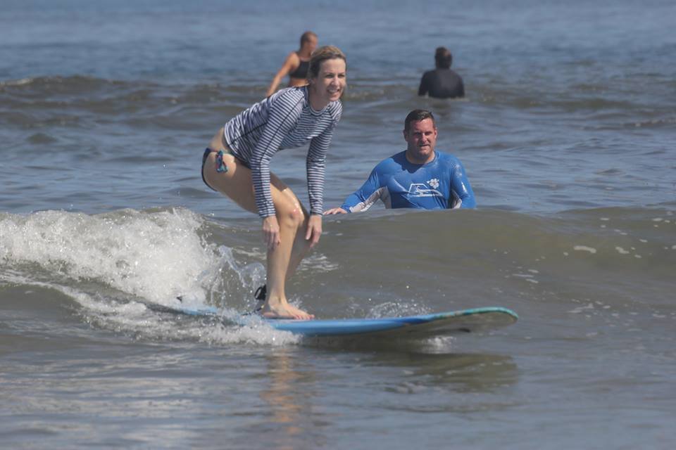 "Surf lesson in Tamarindo, Costa Rica, with a professional instructor guiding students on the beach as they practice surfing techniques on the waves."