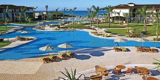 "Scenic drive from Liberia Airport to JW Marriott Guanacaste, passing through lush Costa Rican landscapes with tropical greenery and open roads, heading toward the luxury resort by the Pacific coast."